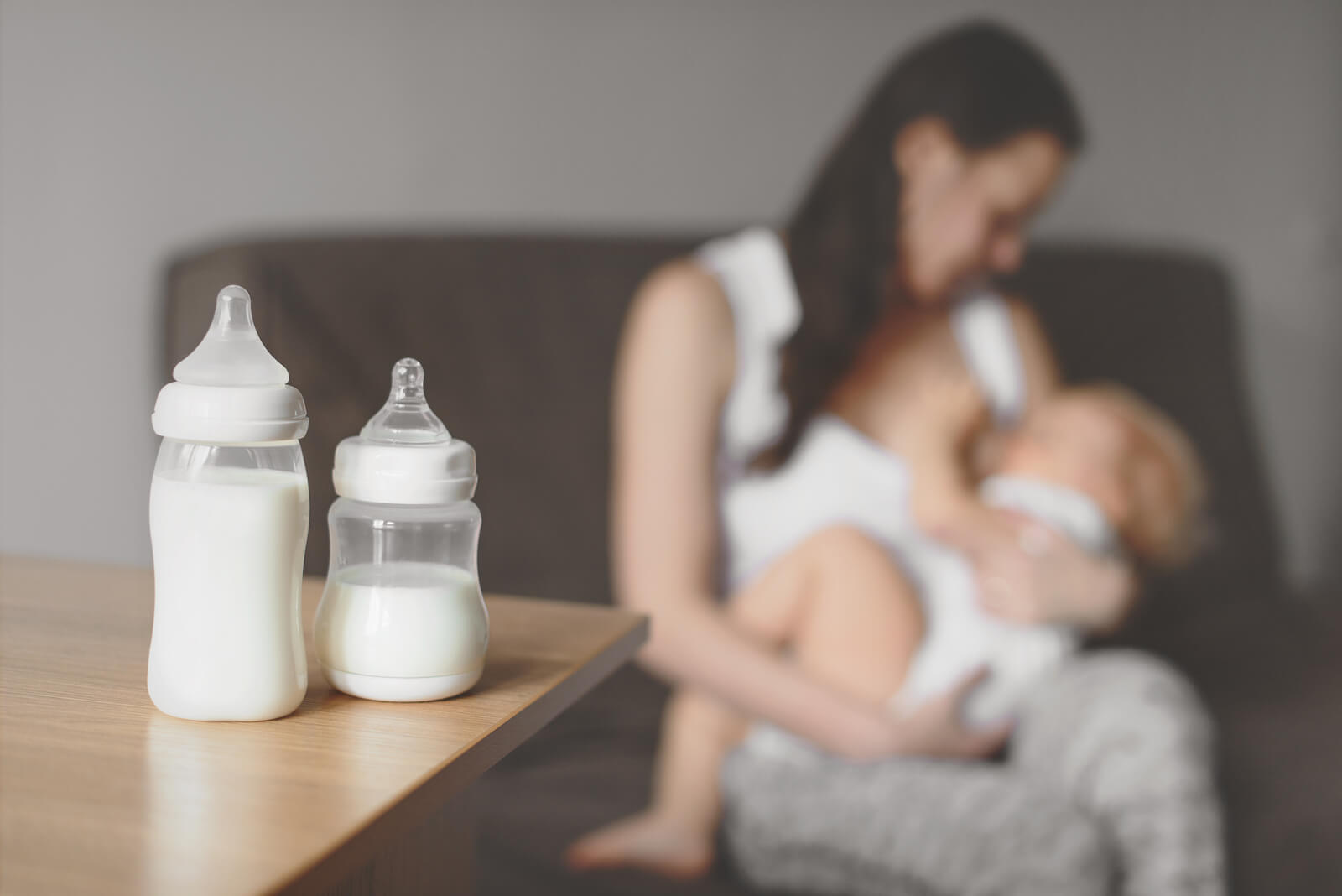 Newborn baby with cute expression is sucking mother's breast and